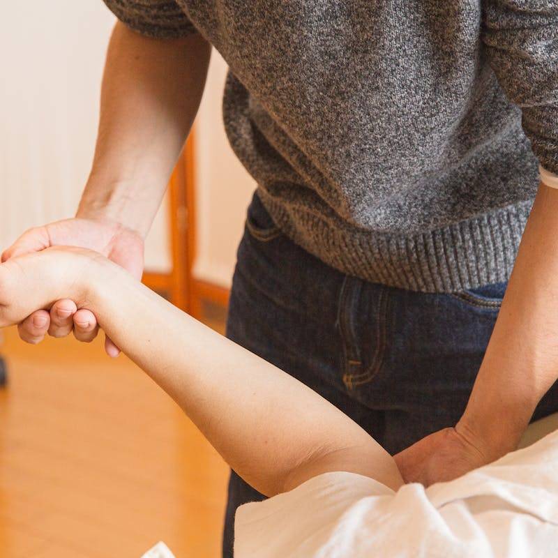 Crop chiropractor massaging hand of patient